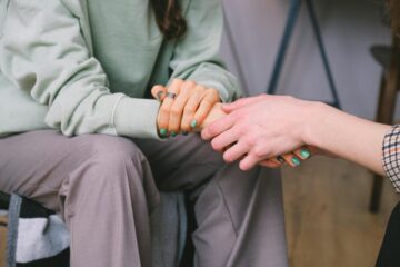 man offering comfort to woman by holding hand