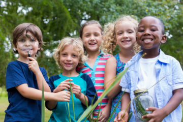 Children smiling holding science tools